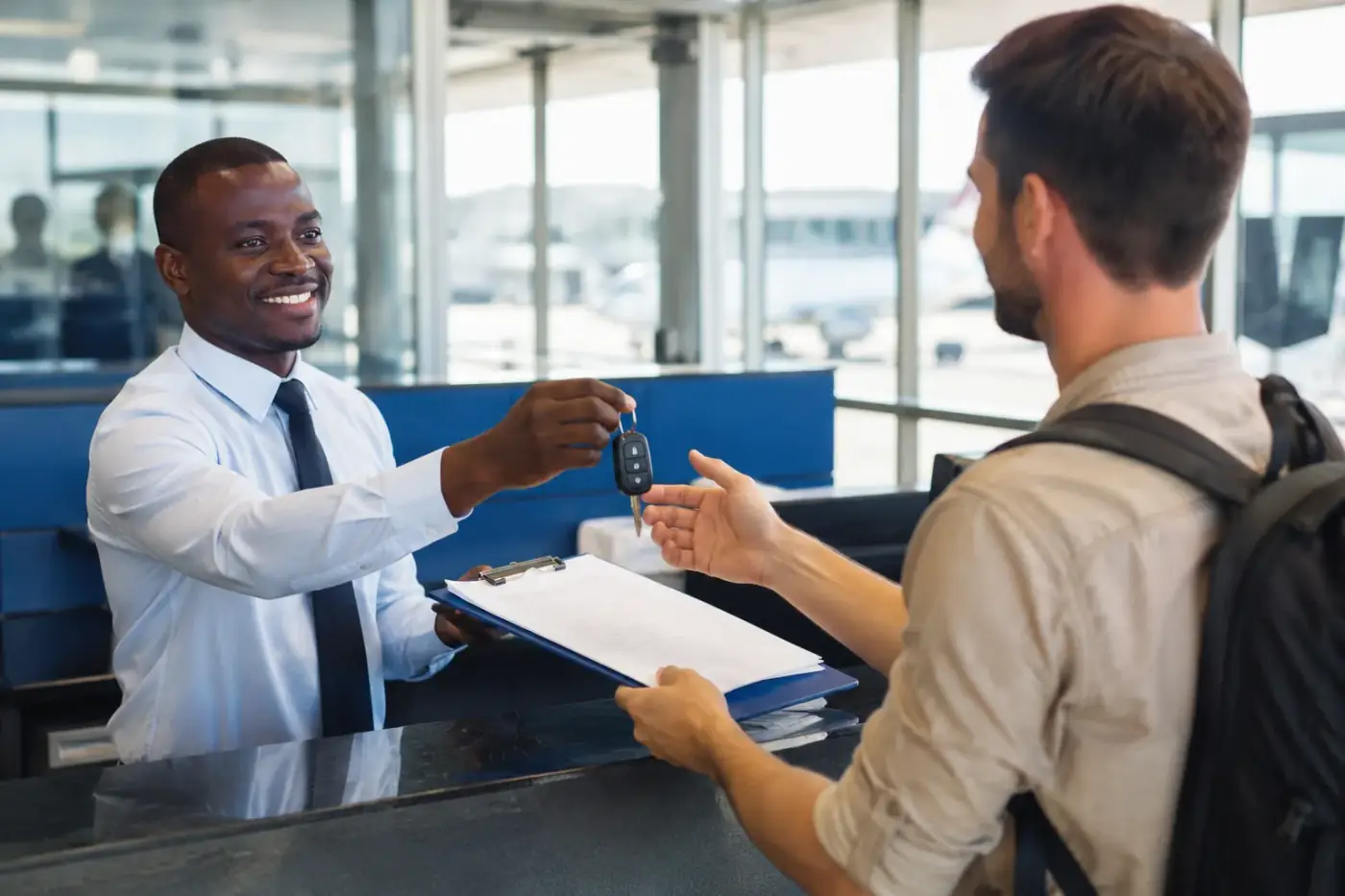 Een medewerker van een autoverhuurbedrijf overhandigt autosleutels op de luchthaven van Luanda