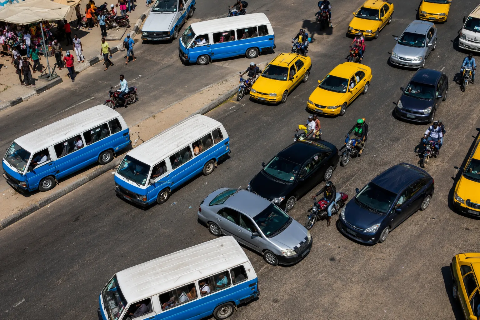 Druk verkeer in Luanda met blauw-witte candongueiro-minibussen en gele taxi’s tussen auto’s en motoren