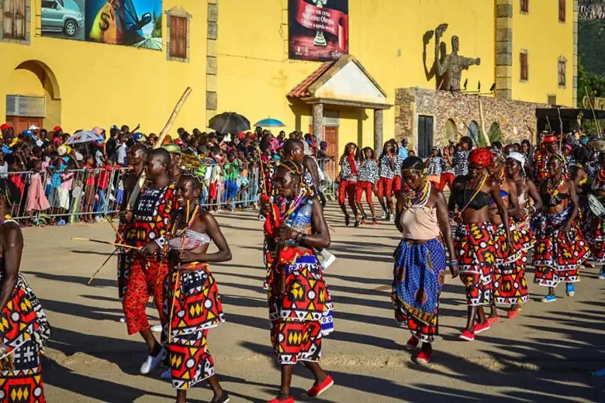 Kleurrijk cultureel dansdefilé voor een geel koloniaal gebouw in Angola